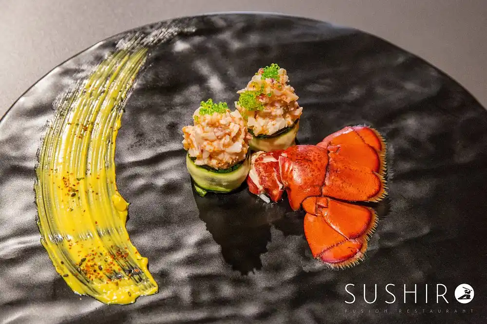 Creazione di sushi con astice servita su piatto nero