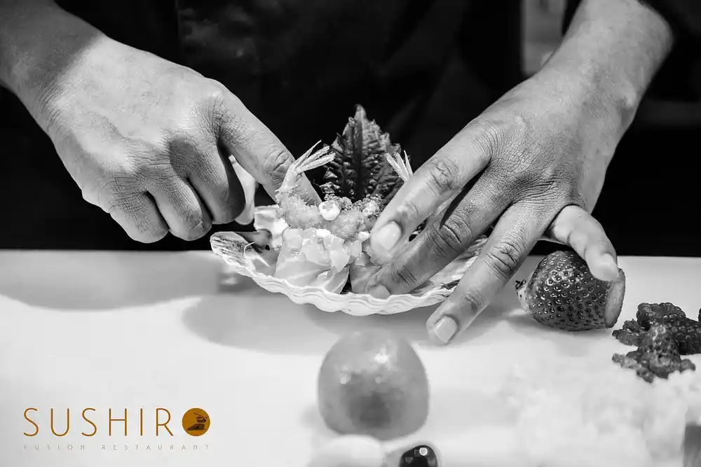 Lo chef prepara una composizione con crostacei e frutta